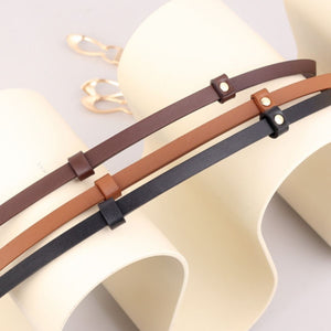 Elegant leather belts in brown, caramel, and black with interlocking buckle detail.