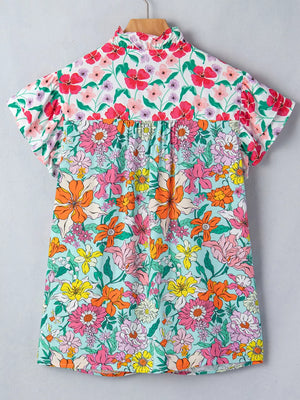 Maternity overshirt with flutter sleeves and a ruffled neckline in a vibrant floral print.