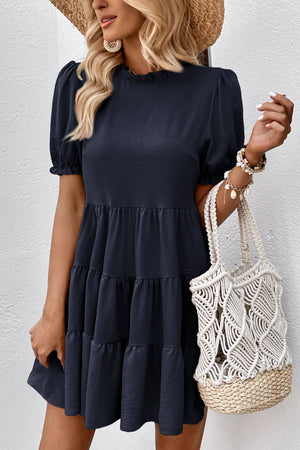 Dark blue tiered mini dress with ruffled neckline and puff sleeves.