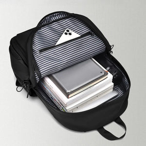 Black commuter backpack interior with striped lining, showing books, tablet, and phone.