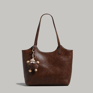 Brown pu leather tote bag with adjustable straps and a fuzzy charm.
