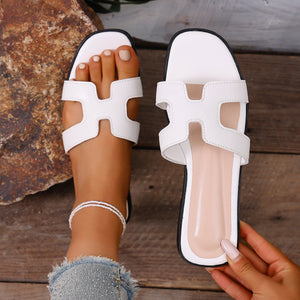 Chic white H-strap open-toe flat sandals with contrast stitching and a beaded anklet.
