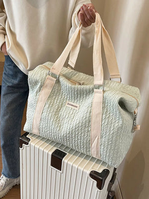 Textured travel bag with cream straps and detachable pouch, shown on a suitcase.