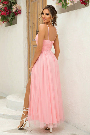 Blush pink tulle gown with spaghetti straps, ruched bodice, and high leg slit.