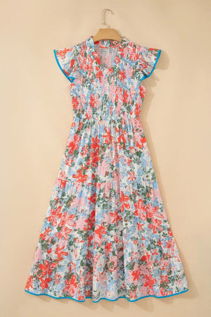 Vibrant floral maxi dress with smocked bodice, flutter sleeves, tiered skirt, and blue trim.