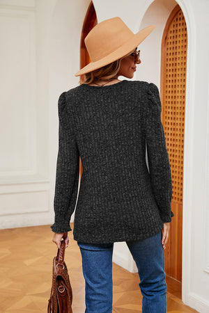 Textured knit blouse in black with long sleeves, puffed shoulders, and ruffled cuffs.