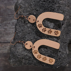 Wooden arch earrings in camel with engraved paw prints and copper hooks.