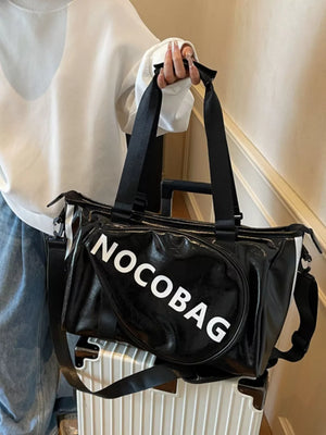 Black leather duffel bag with white text and detachable strap.
