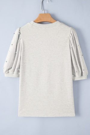 Light gray sweatshirt with embellished puff sleeves and pearl details.