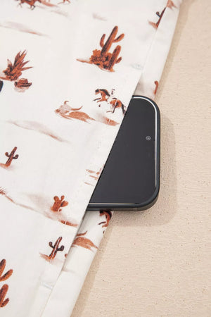 Desert Motif Adjustable Jumpsuit in beige cotton with cactus and horse print, showing a side pocket with a phone.