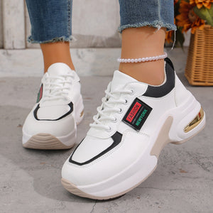 White lace-up sneakers with black and gold accents and a chunky sole.