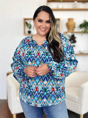 Prismatic ikat blouse with voluminous sleeves and V-neck in green and blue tones.