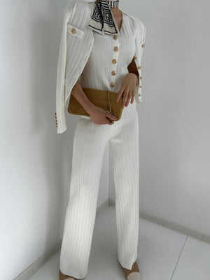 White ribbed knit ensemble with gold buttons, featuring a cardigan and pants.