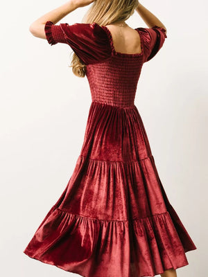 Burgundy velvet midi dress with smocked bodice and ruffled short sleeves.