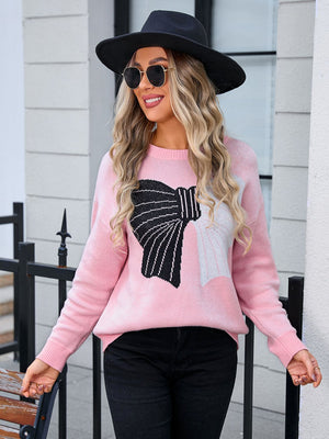 Pink knit sweater with a black and white graphic bow detail.