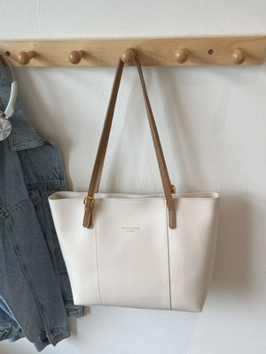 White structured tote bag with brown trim and gold hardware, faux leather.
