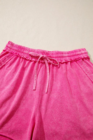 Acid-washed hot pink cotton drawstring shorts with pockets and elastic waistband.