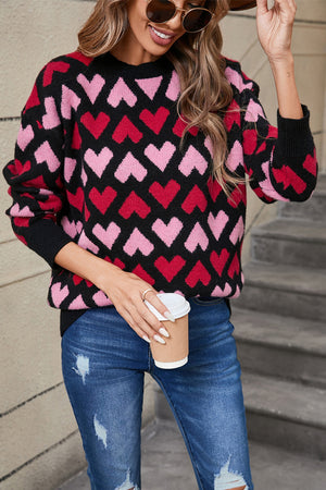 Black acrylic sweater with allover pink and red heart pattern, crew neck, long sleeves.