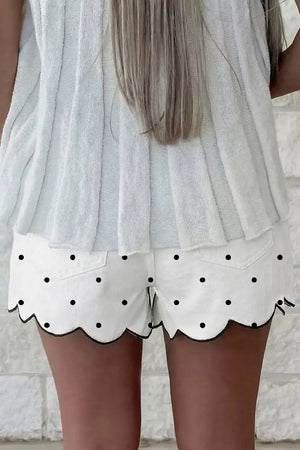 White chino shorts with black polka dots and scalloped hem detail.