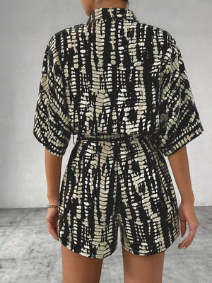 Black and white striped belted romper with collared neckline and short sleeves.