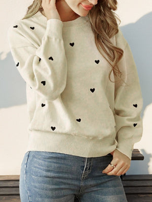 Cream acrylic sweater with scattered black heart intarsia, balloon sleeves, and crew neck.