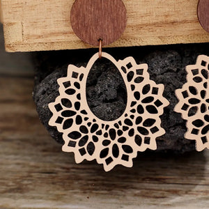 Floral laser-cut wooden drop earrings in tan with intricate cutout pattern.
