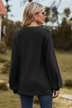Black waffle knit raglan sweater with laser cut detail on sleeves