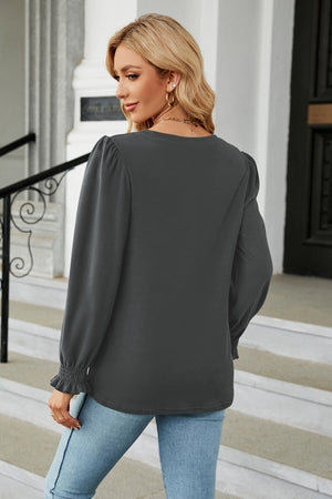 Dark gray long sleeve blouse with smocked cuffs and puff sleeves.