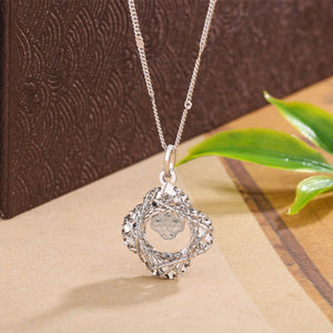 Silver clover pendant necklace with intricate woven detail.
