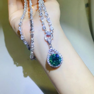 Silver moissanite halo pendant necklace with a large emerald-green pear-shaped center stone.