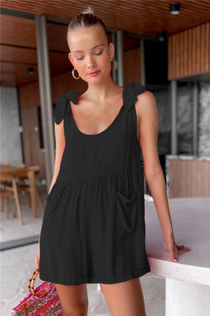 Black romper with gathered waist, bow shoulder straps, and pockets.