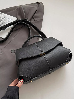 Black textured geometric flap shoulder bag with contrast stitching and gold hardware.