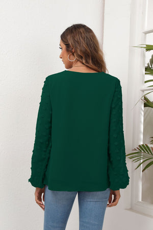 Forest green blouse with pom-pom detail on balloon sleeves and V-neck.