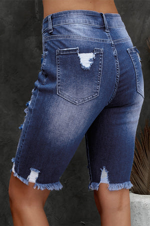 Ripped knee denim bermuda shorts in medium wash with frayed hem and distressed details.