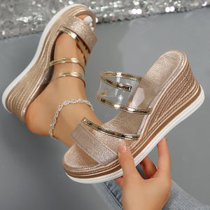 Gold glitter strap open-toe wedge sandals with clear straps and a braided wedge detail.
