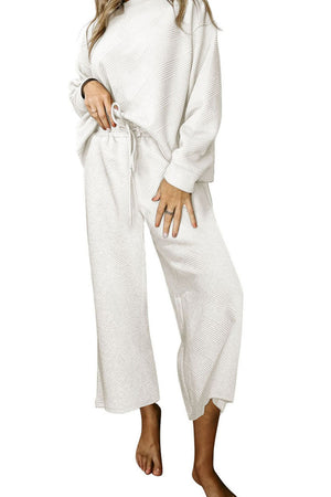 White loungewear set with textured pattern, crew neck top and wide leg pants.
