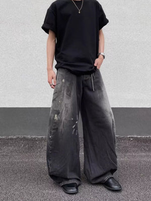 Men's wide leg distressed jeans in charcoal grey denim with paint splatters.