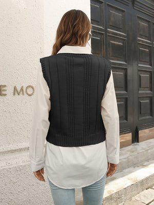 Black cable knit crop vest sweater with ribbed trim, worn over a white shirt.