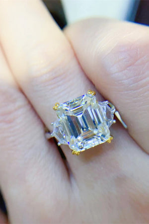 Emerald cut trilogy ring in silver with gold accents and clear stones.