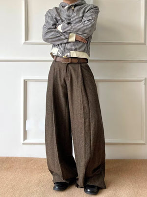 Men's brown wide-leg pleated trousers with a textured fabric and a brown belt.