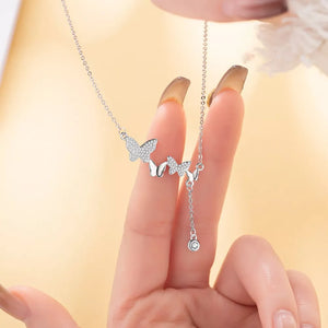 Delicate silver necklace with three sparkling butterfly charms and a dangling zircon accent.