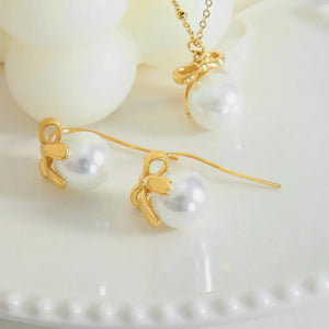 Gold pearl bow drop earrings with 18K gold plating.