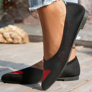 Black knit pointed flats with red geometric pattern detail.