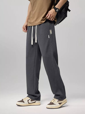 Relaxed fit gray drawstring sweatpants with textured fabric and a small logo patch.