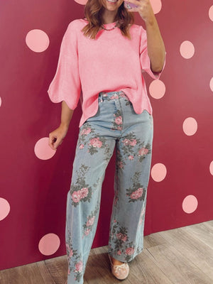 Pink knit top with scalloped sleeves and hem, paired with light wash floral print wide leg jeans.