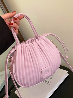 Pink pleated mini bucket bag with drawstring closure and square detail.