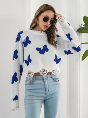 White cropped knit sweater with distressed hem and blue butterfly print.