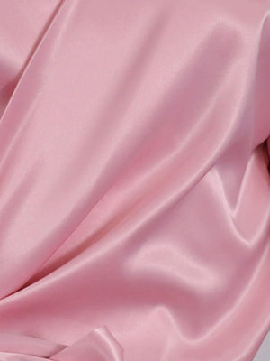 Blush pink satin blouse with draped detail and brooch.