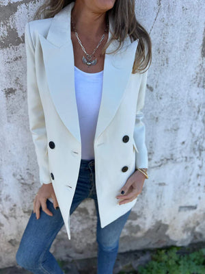 Ivory double-breasted blazer with sculpted lapels and dark buttons, styled with a white tank and jeans.