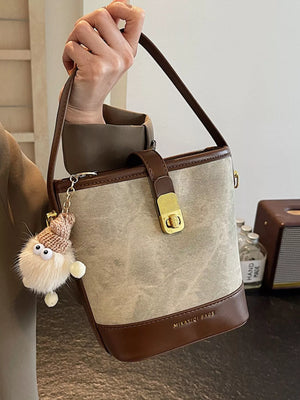 Elegant bucket bag in light brown canvas with dark brown PU leather trim and gold hardware.